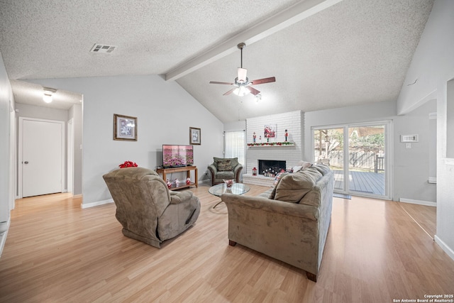 living area with lofted ceiling with beams, light wood-type flooring, visible vents, a ceiling fan, and a fireplace
