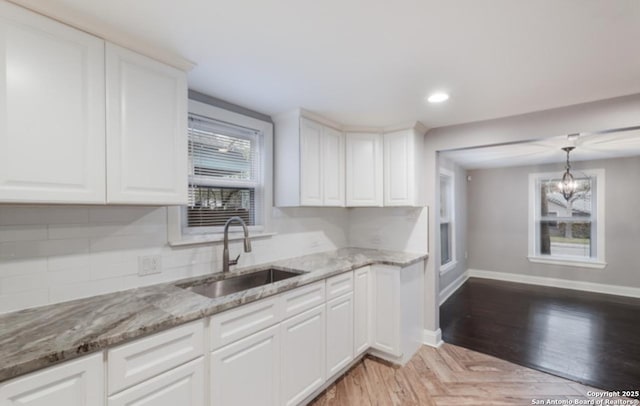 1244 Clower, San Antonio, TX 78201 - kitchen featuring a sink, a notable chandelier, tasteful backsplash, white cabinetry, and baseboards