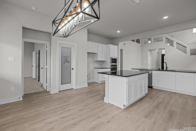 133 Bailey Blf, San Antonio, TX 78253 - kitchen with white cabinetry, dark countertops, a kitchen island, light wood-style floors, and appliances with stainless steel finishes