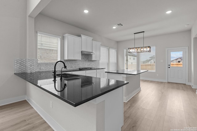 133 Bailey Blf, San Antonio, TX 78253 - kitchen with light wood finished floors, dark countertops, a sink, a center island, and tasteful backsplash