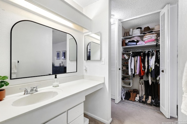 6807 Burnley, San Antonio, TX 78239 - bathroom featuring baseboards, vanity, a textured ceiling, and a walk in closet