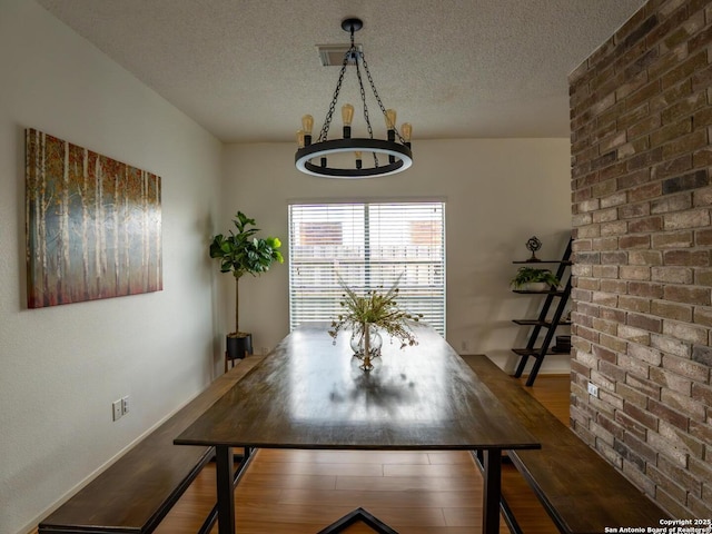 dining room featuring an inviting chandelier, wood finished floors, and a textured ceiling