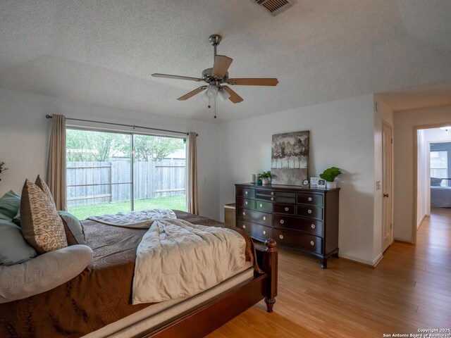 bedroom with multiple windows, a textured ceiling, and light wood-style floors