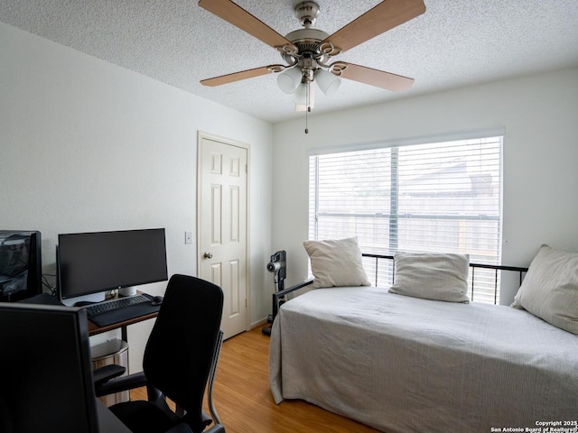 bedroom with light wood finished floors, a textured ceiling, and ceiling fan