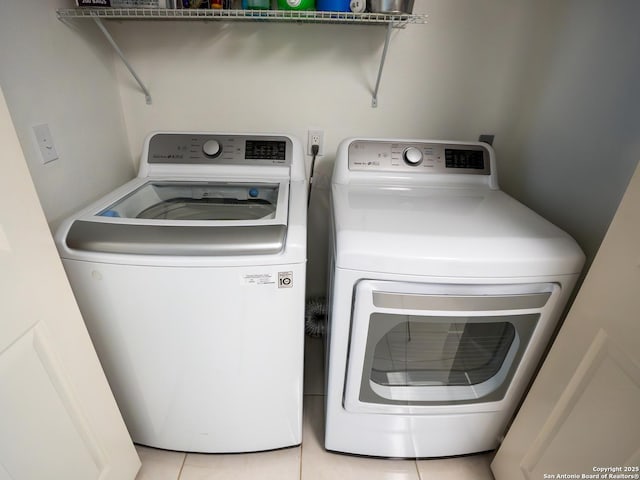 washroom featuring separate washer and dryer, light tile patterned flooring, and laundry area