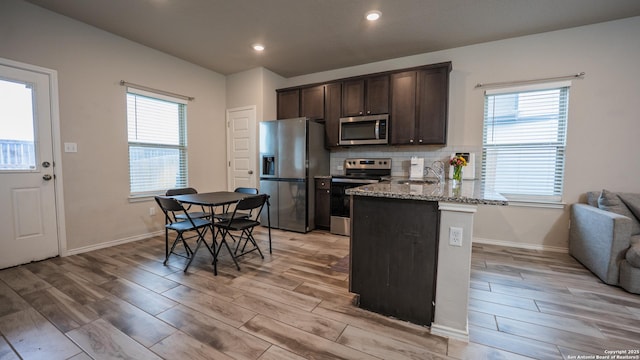 kitchen featuring dark brown cabinets, light wood-type flooring, stainless steel appliances, and a sink