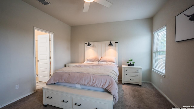 carpeted bedroom featuring ensuite bath, baseboards, a ceiling fan, and visible vents