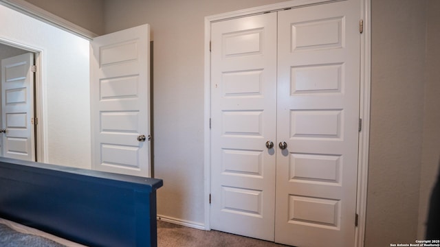 unfurnished bedroom with dark colored carpet, baseboards, and a closet