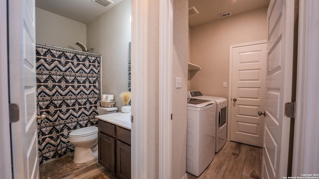 washroom featuring washing machine and dryer, a textured wall, visible vents, and light wood-type flooring