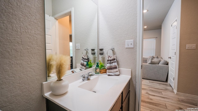 bathroom featuring a textured wall, wood finished floors, recessed lighting, and vanity