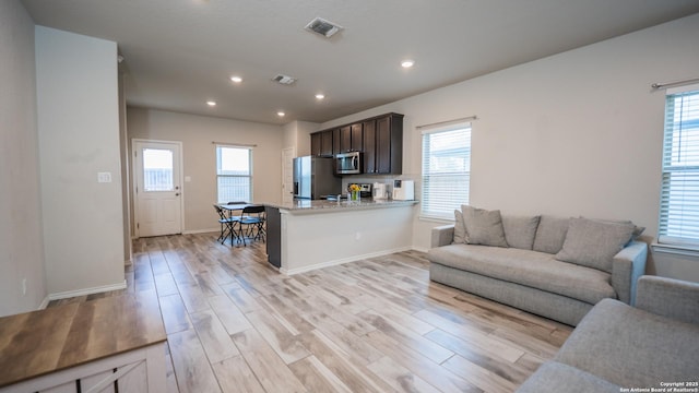 living room with a healthy amount of sunlight, visible vents, and light wood-style flooring