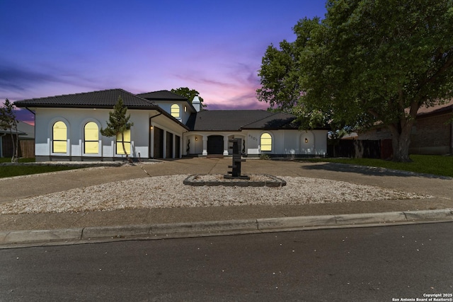 view of front of property featuring a garage, driveway, and a tile roof