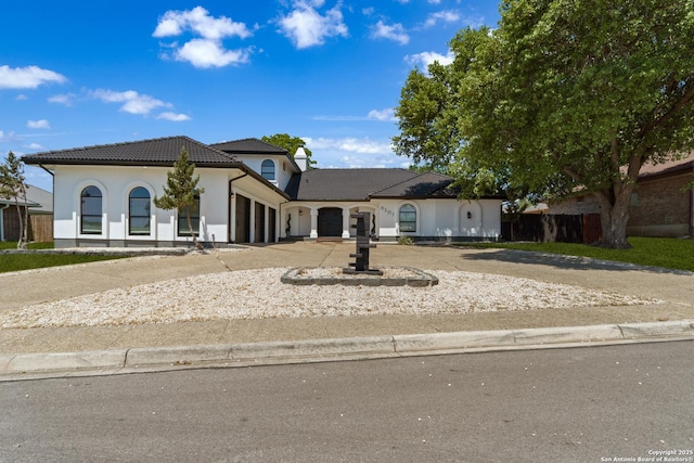 view of front of home featuring an attached garage, a tiled roof, stucco siding, and concrete driveway
