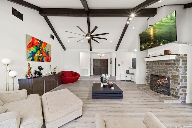 living area with a brick fireplace, beam ceiling, a ceiling fan, and visible vents