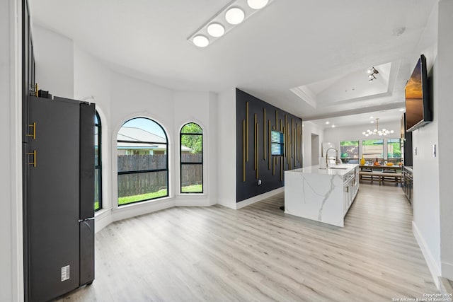kitchen with light wood-type flooring, freestanding refrigerator, a notable chandelier, and a tray ceiling