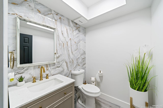 bathroom featuring backsplash, wood finished floors, toilet, vanity, and baseboards