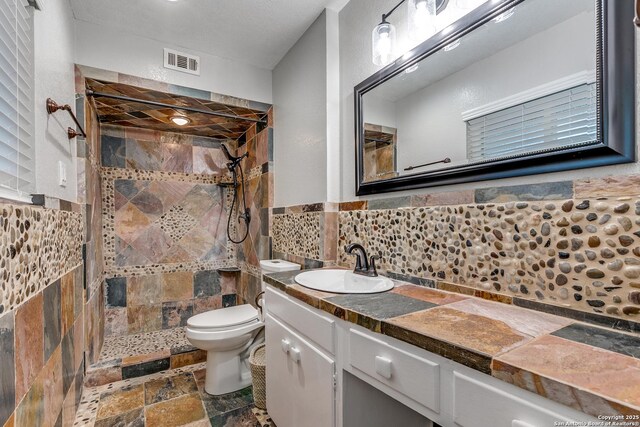 105 Parade, San Antonio, TX 78213 - bathroom featuring stone tile floors, visible vents, toilet, and tiled shower
