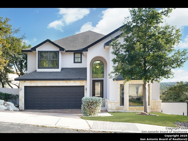 traditional home with roof with shingles, a front lawn, driveway, an attached garage, and stucco siding