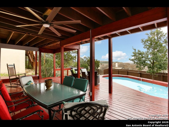 wooden deck featuring ceiling fan, a fenced backyard, a fenced in pool, and outdoor dining space