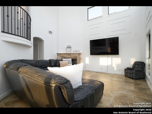 living room with a fireplace, a high ceiling, visible vents, and baseboards