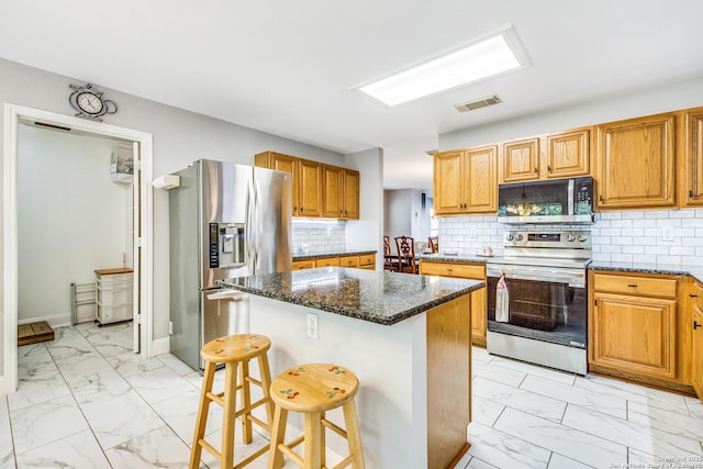 kitchen with a center island, dark stone countertops, marble finish floor, appliances with stainless steel finishes, and visible vents