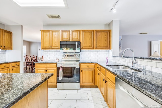 kitchen with a sink, dark stone countertops, tasteful backsplash, visible vents, and appliances with stainless steel finishes