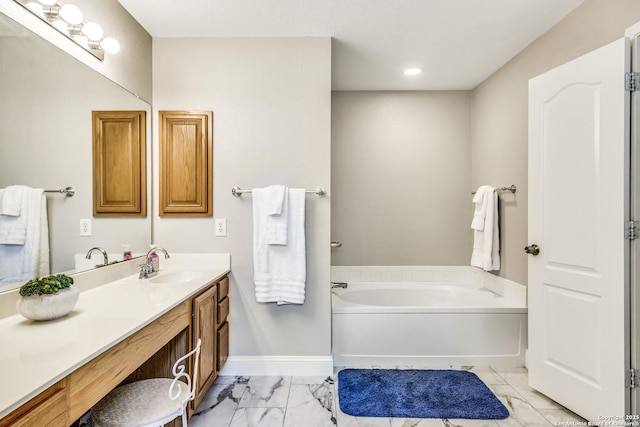 full bath featuring a garden tub, vanity, marble finish floor, baseboards, and recessed lighting