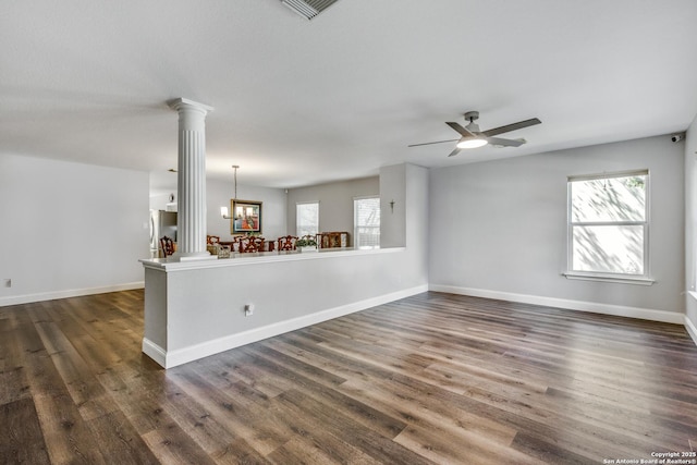 unfurnished living room with ceiling fan, baseboards, dark wood-type flooring, and ornate columns