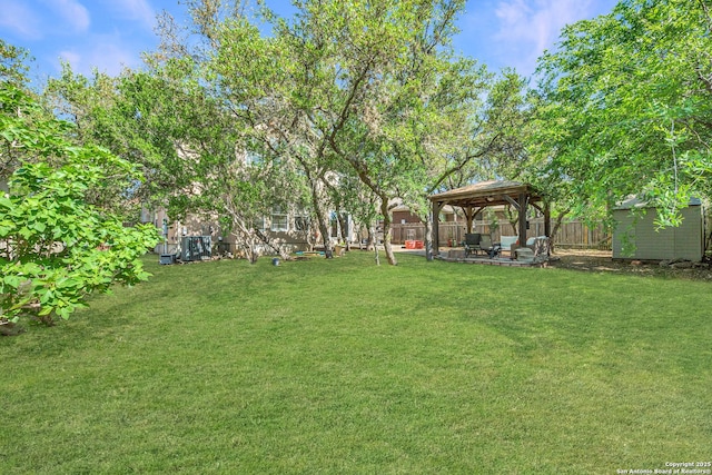 view of yard featuring a gazebo, a patio area, a shed, a fenced backyard, and an outdoor structure