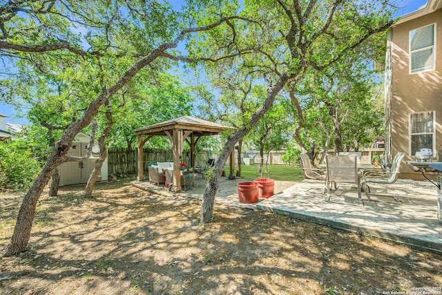 view of yard with a fenced backyard, a storage shed, an outbuilding, a patio, and a gazebo