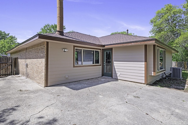 9400 Woodland Hls, San Antonio, TX 78250 - back of house with fence, a shingled roof, central AC, a patio, and brick siding
