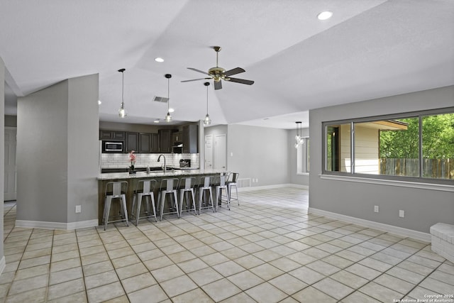 9400 Woodland Hls, San Antonio, TX 78250 - interior space with backsplash, a breakfast bar, a ceiling fan, a sink, and stainless steel microwave