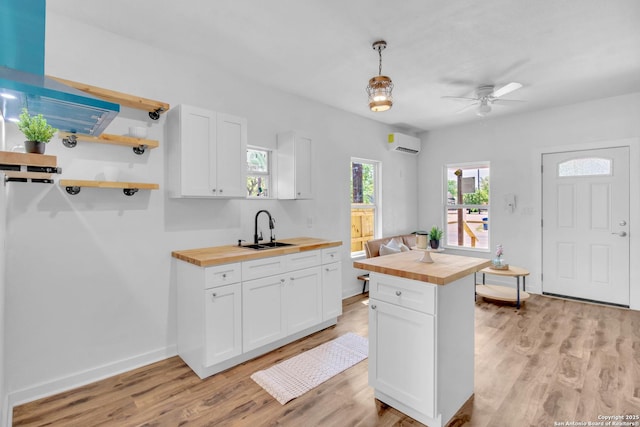 2201 San Fernando, San Antonio, TX 78207 - kitchen with white cabinets, wooden counters, open shelves, a sink, and light wood-type flooring