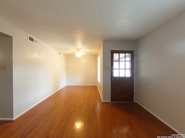 entrance foyer featuring a textured ceiling, baseboards, visible vents, wood finished floors, and ceiling fan