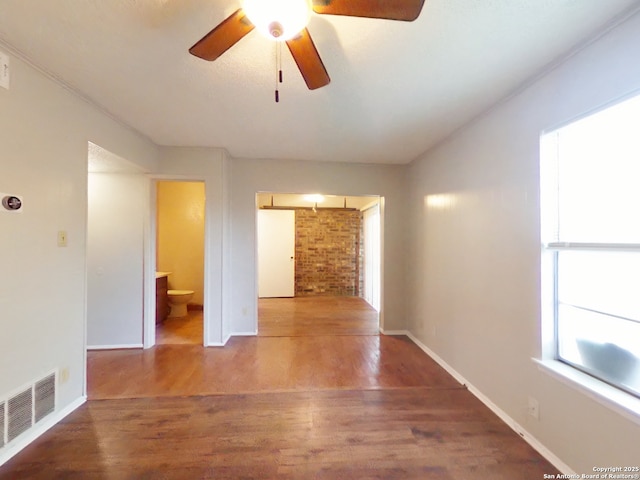 unfurnished room with baseboards, a ceiling fan, wood finished floors, and visible vents