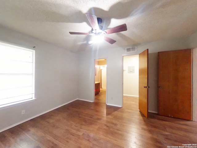unfurnished bedroom featuring a textured ceiling, wood finished floors, visible vents, and baseboards
