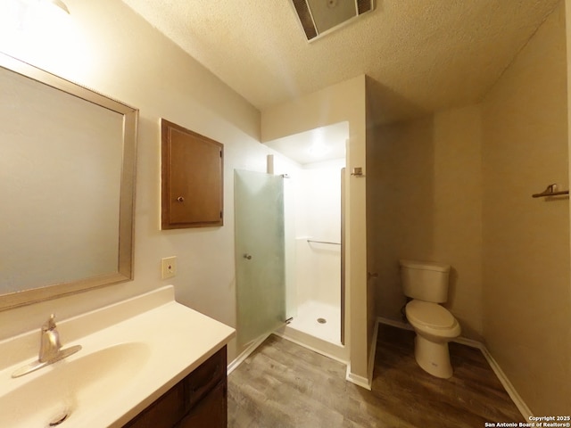 full bath featuring a shower stall, wood finished floors, visible vents, vanity, and a textured ceiling