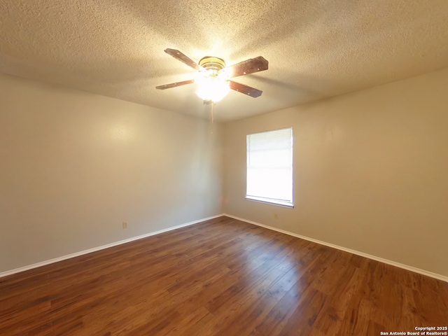 empty room with a textured ceiling, a ceiling fan, baseboards, and dark wood-style flooring