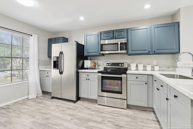 3654 Candlehead, San Antonio, TX 78244 - kitchen with light stone counters, a sink, light wood-type flooring, stainless steel appliances, and blue cabinetry