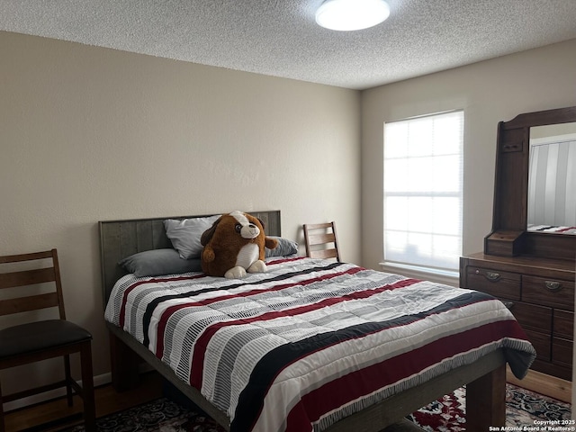 bedroom featuring wood finished floors and a textured ceiling