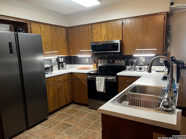 kitchen with backsplash, stainless steel appliances, light countertops, and a sink
