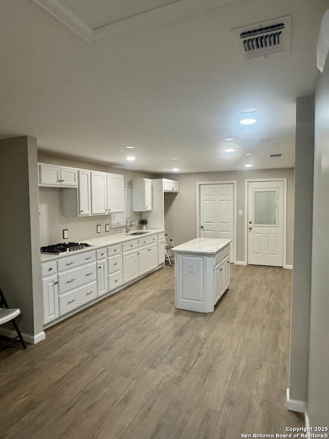 531 Cottonwood, San Antonio, TX 78225 - kitchen with wood finished floors, visible vents, a sink, stainless steel gas cooktop, and white cabinetry