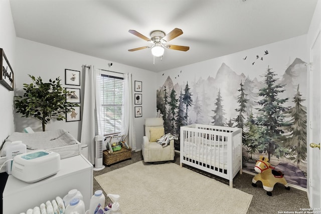 carpeted bedroom with ceiling fan and a crib