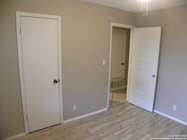 unfurnished bedroom featuring baseboards, visible vents, and light wood-style flooring