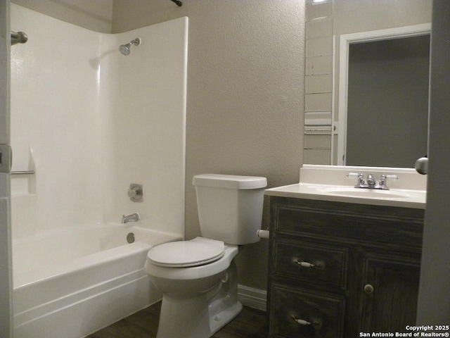 bathroom featuring vanity, a textured wall, bathing tub / shower combination, and toilet