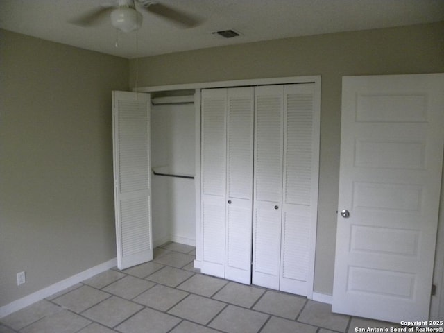 unfurnished bedroom featuring ceiling fan, visible vents, light tile patterned floors, baseboards, and a closet