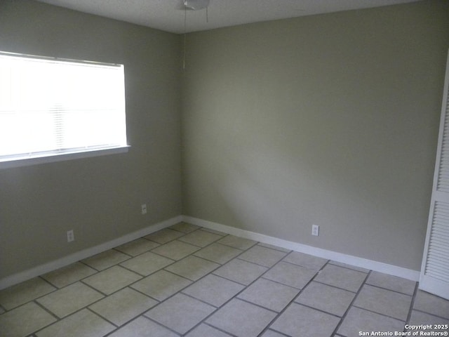 unfurnished room with light tile patterned floors, baseboards, and ceiling fan