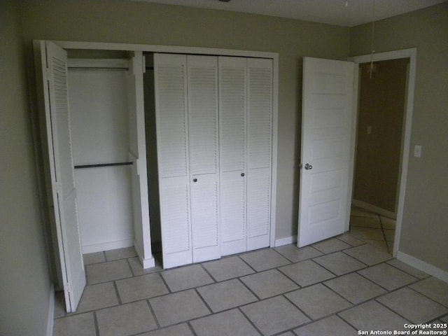 unfurnished bedroom with baseboards, light tile patterned floors, and a closet