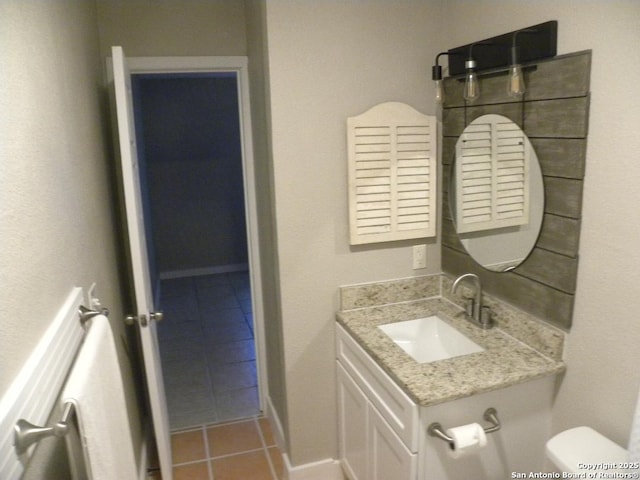 half bathroom with vanity, tile patterned flooring, and toilet