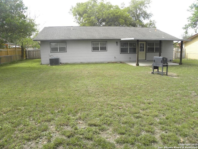 rear view of house featuring fence, a patio, a lawn, and central AC